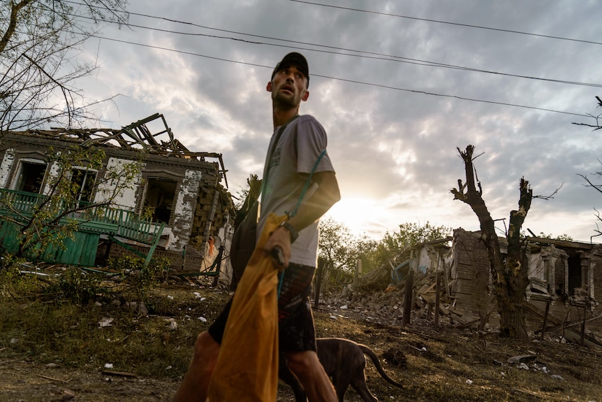 A man walks past the damaged homes from a rocket attack just as the sun rises.