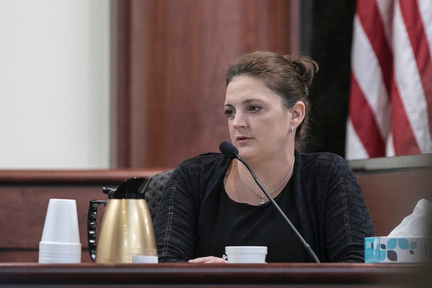 Amber Kyzer speaks into a microphone in a court room.