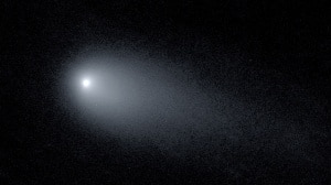 Blurry black-and-white image of a comet surrounded by a halo of light, with a large streak to one side