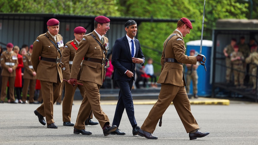 Rishi Runak walks alongside military recruits.