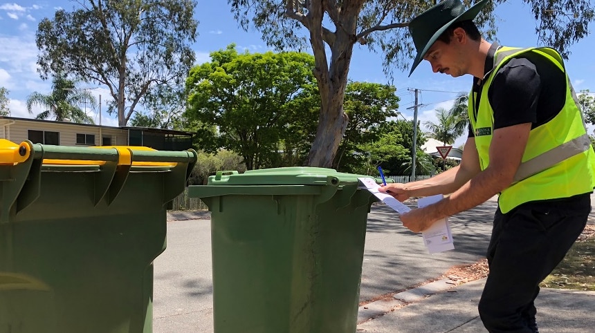 A council officer inspects a wheelie bin