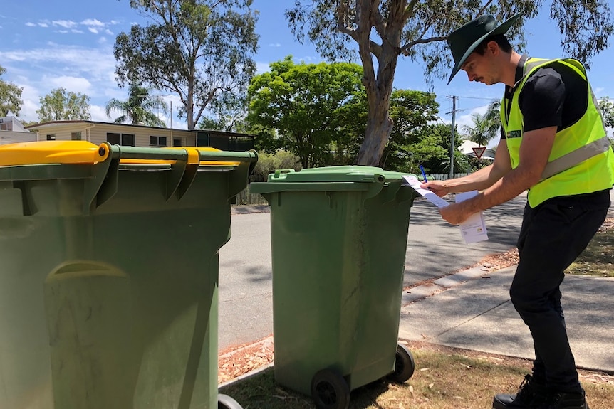 A council officer inspects a wheelie bin