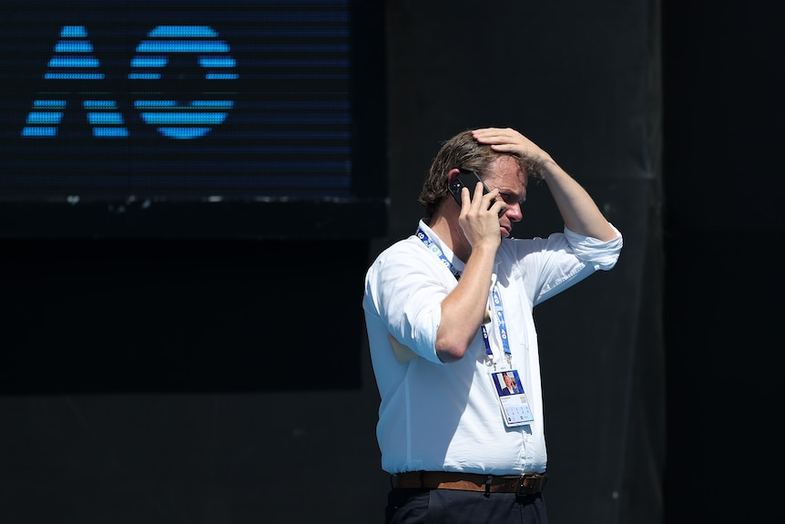 An official holds his head while on the phone