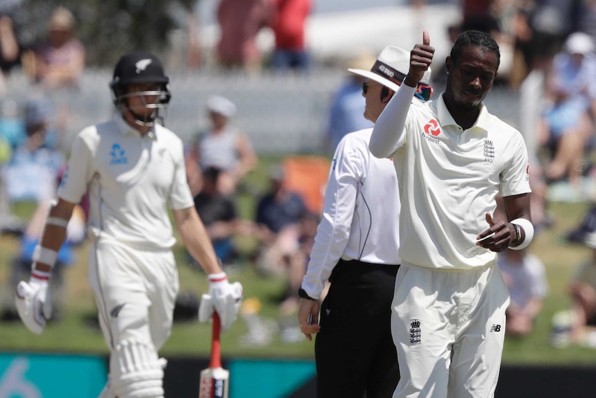 A bowler gives a thumbs up to the crowd as he walks back to his mark.