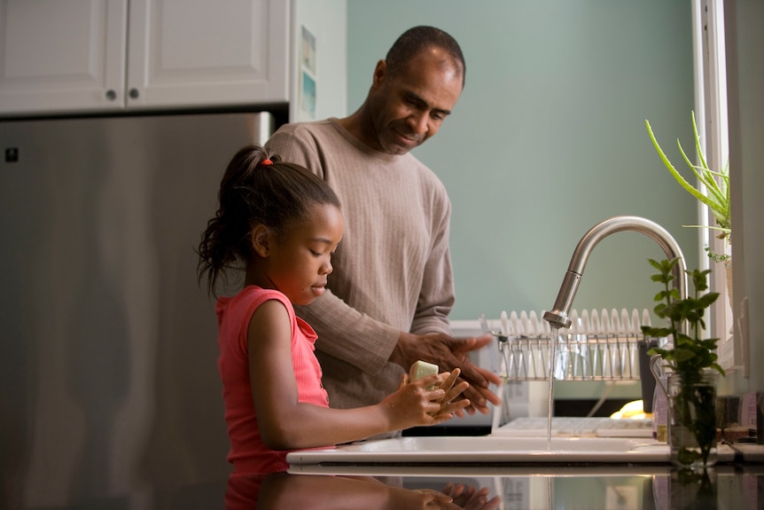 Father talking to daughter at sink
