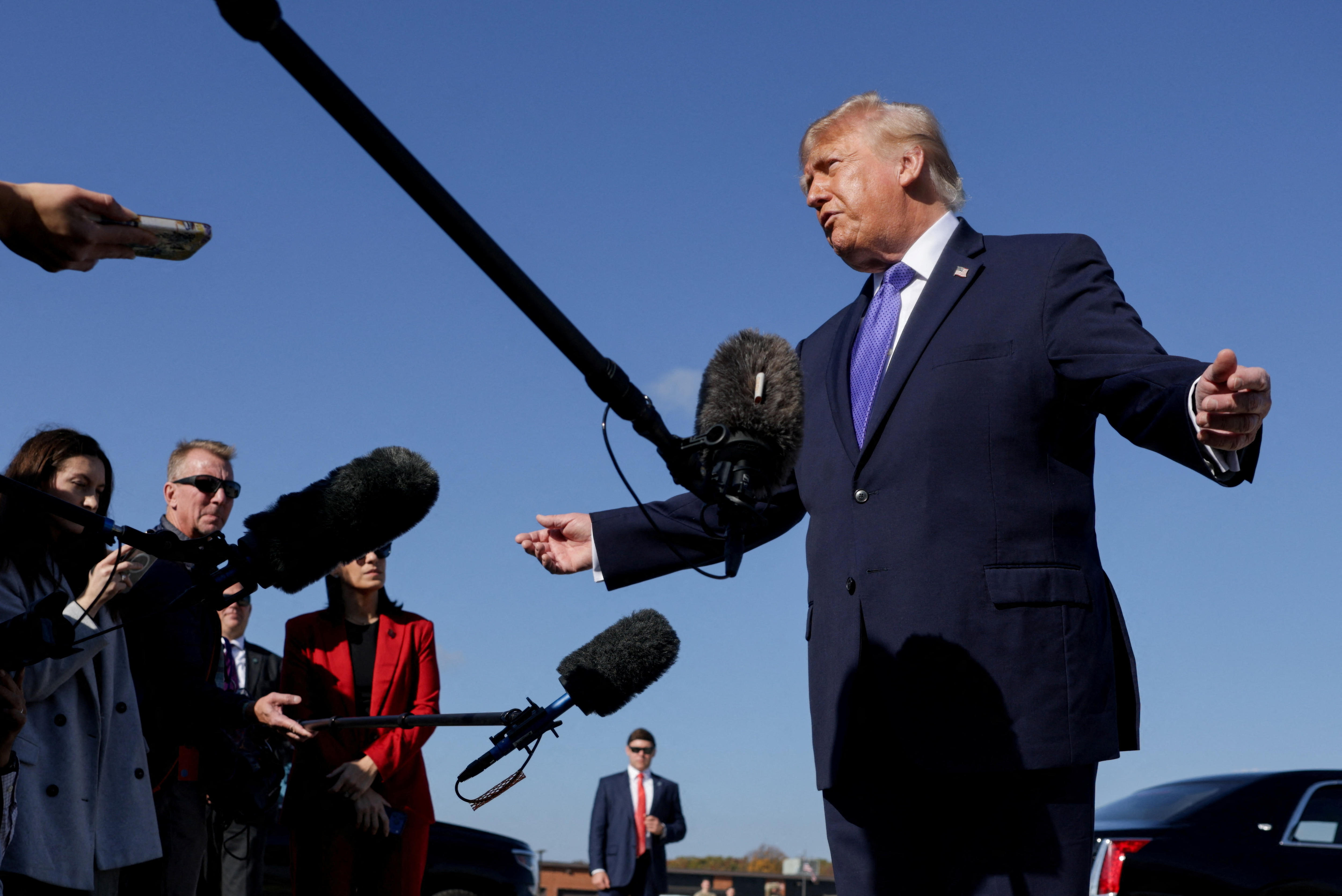Trump talks into a boom microphone on a tarmac