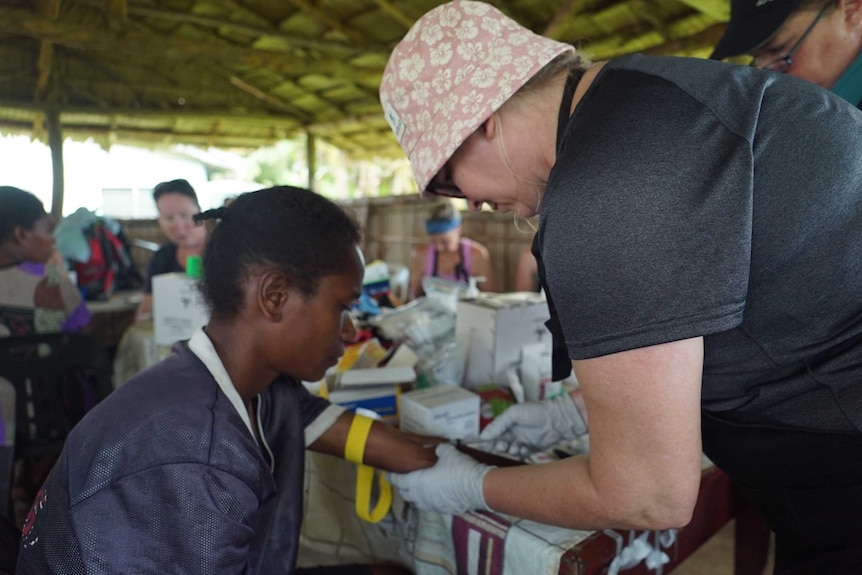No Roads to Health volunteer Katherine Teagle takes a blood sample from a patient at Tufi Station.