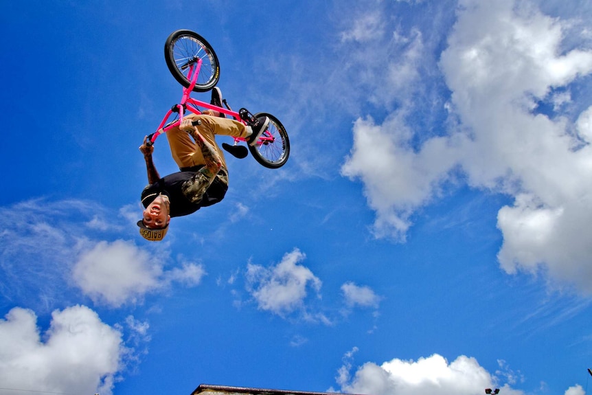 A man is captured mid trick - upside down on his BMX bike