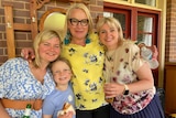 Three women and a young child smiling for a photo.