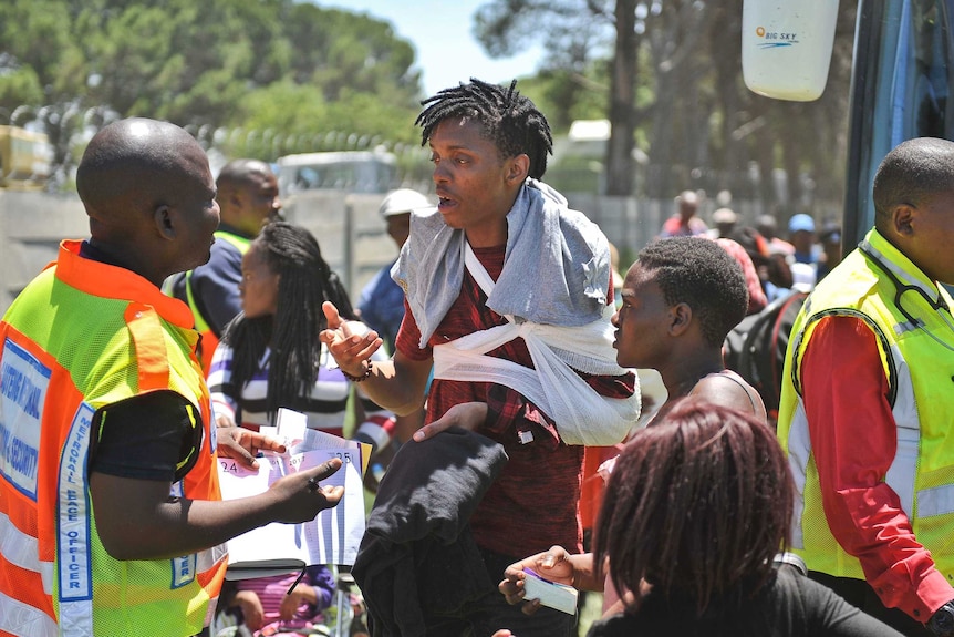 Long shot of an injured train passenger speaking to an emergency worker.