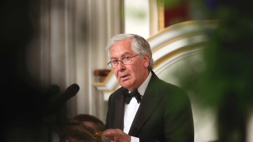 Mervyn King looks toward the camera while he addresses an audience in London.