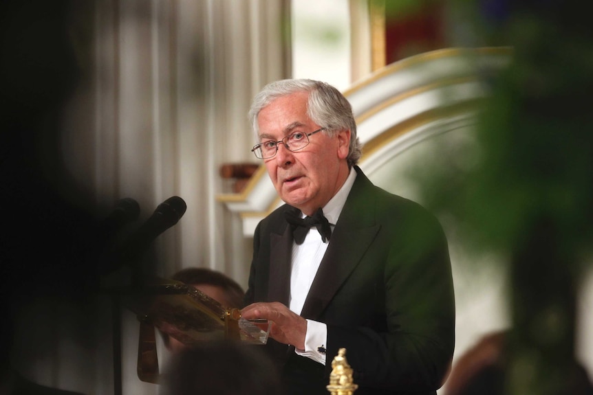 Mervyn King looks toward the camera while he addresses an audience in London.