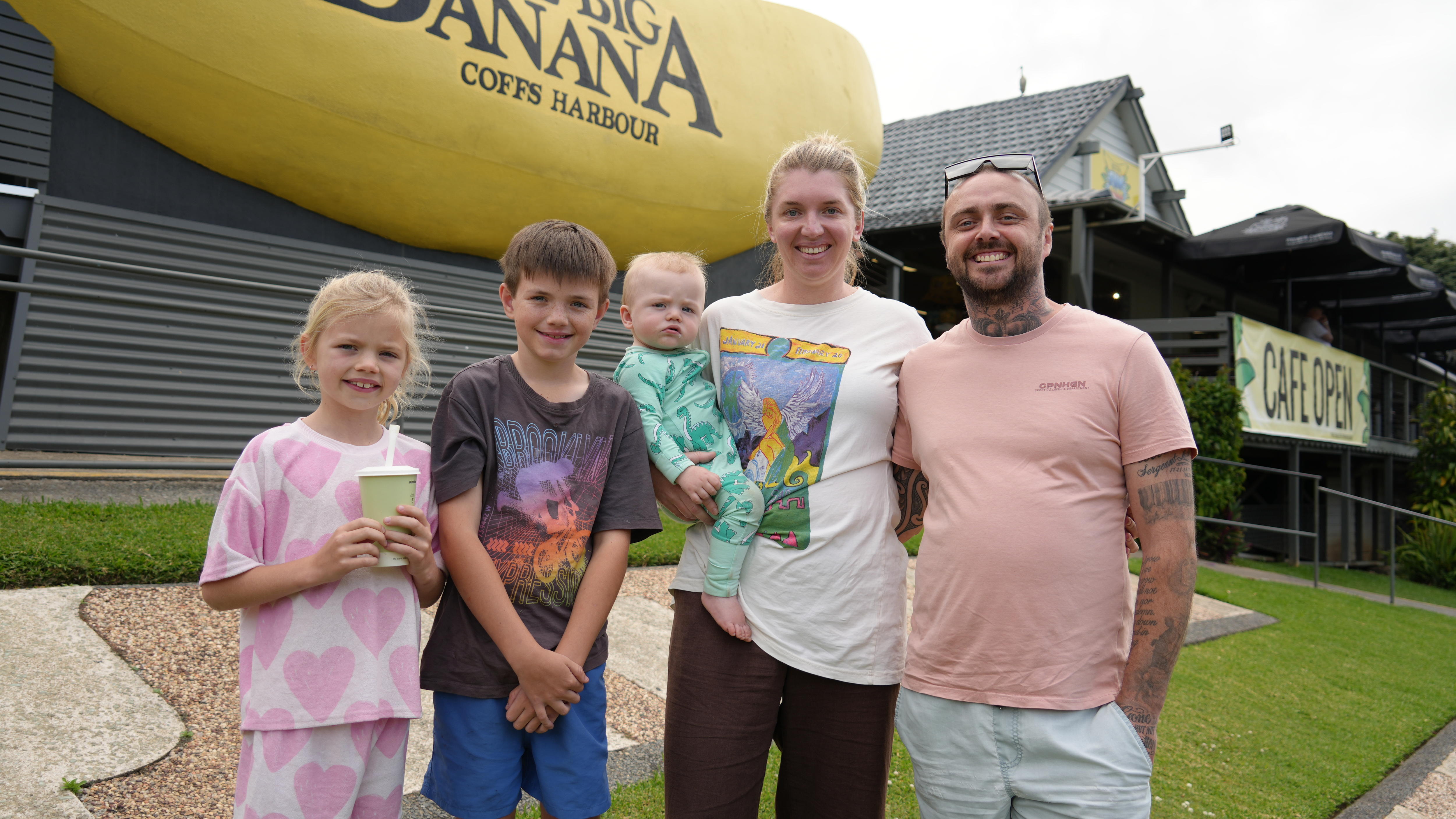 Mother, father and their family of three young children pose in front of the Big Banana.