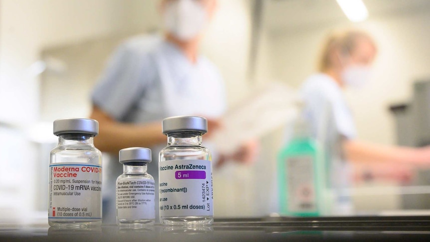 Glass vials in the foreground, masked people in background