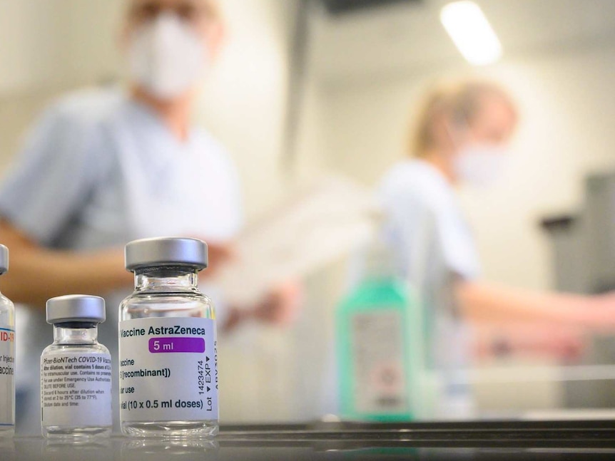 Glass vials in the foreground, masked people in background