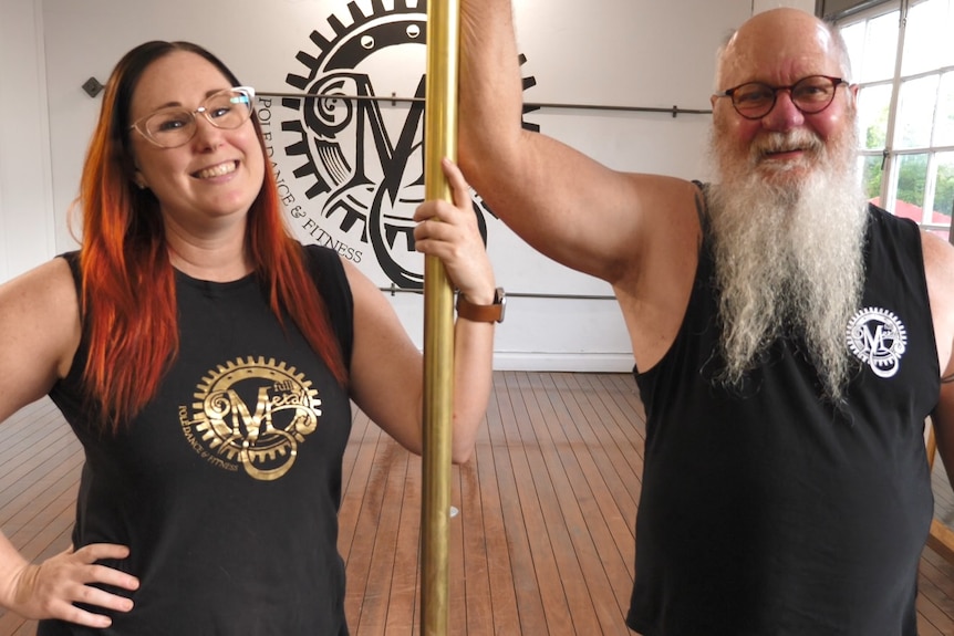 Tamara and Allan stand in an airy studio and hold on to a pole