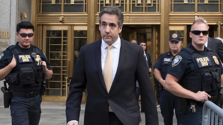 Michael Cohen leaves court after pleading guilty surrounded by police.