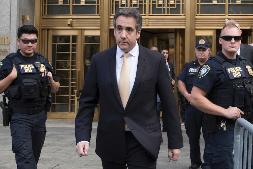 Michael Cohen leaves court after pleading guilty surrounded by police.