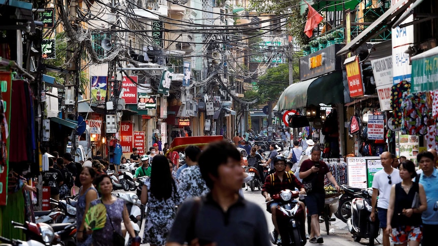 People walk down a crowded Vietnamese road.