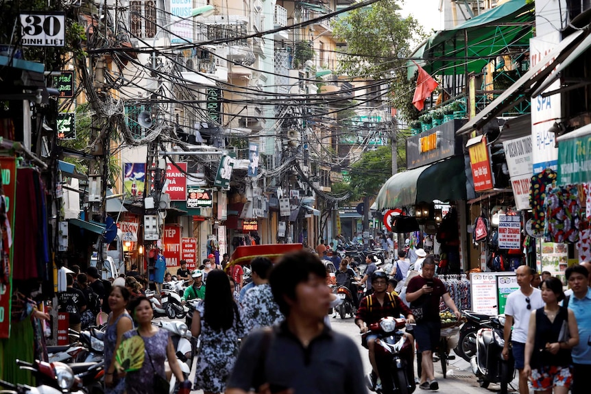 People walk down a crowded Vietnamese road.