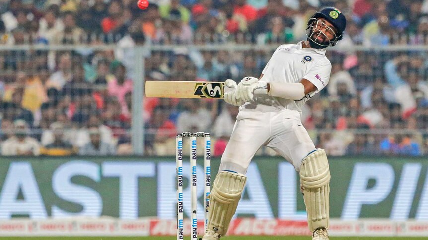 An Indian batsman wearing a helmet dodges a rising pink ball against Bangladesh.