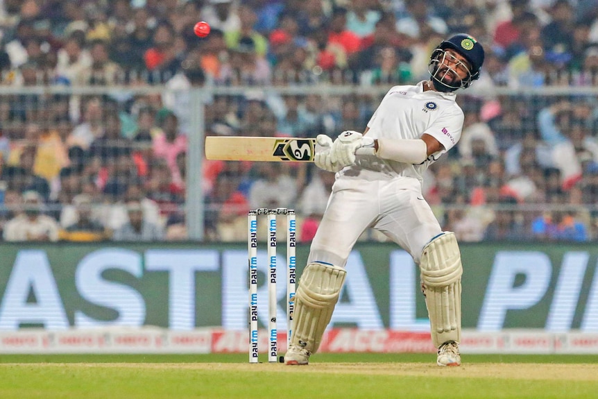 An Indian batsman wearing a helmet dodges a rising pink ball against Bangladesh.