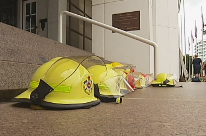 Up to 10 firefighter helmets sit on the steps of NT Parliament House