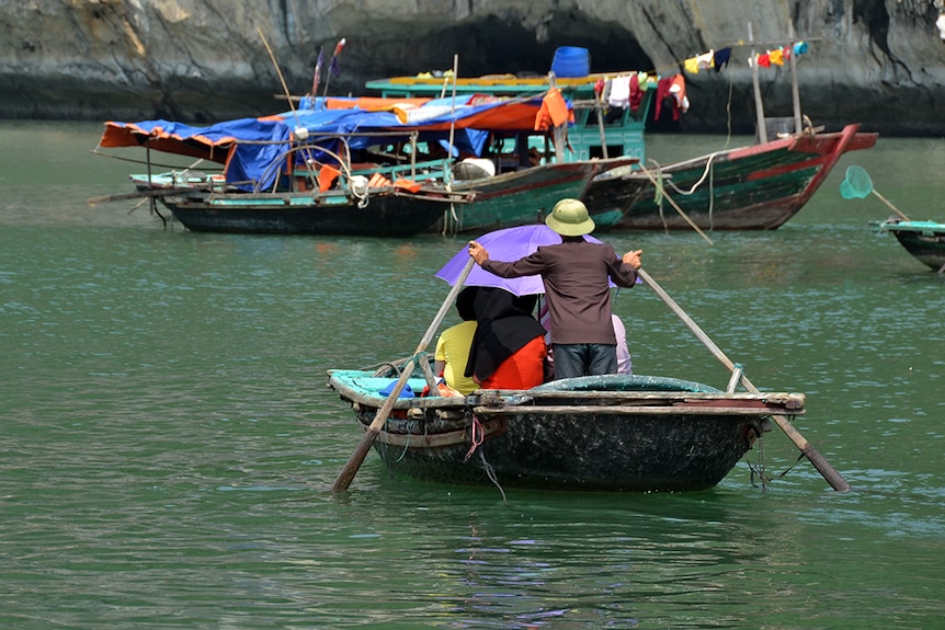 People being transported on small boats on Vietnam in Ha Long Bay.