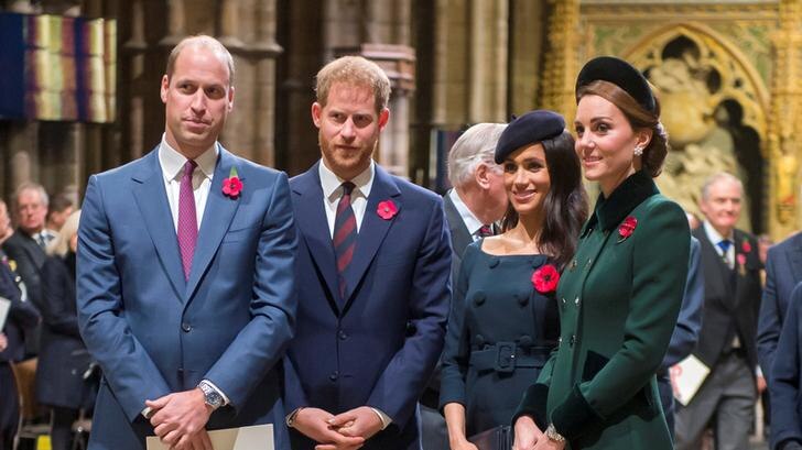 Prince William stands to the left, with Prince Harry to his right, followed by Meghan and Kate. The foursome sport poppies.