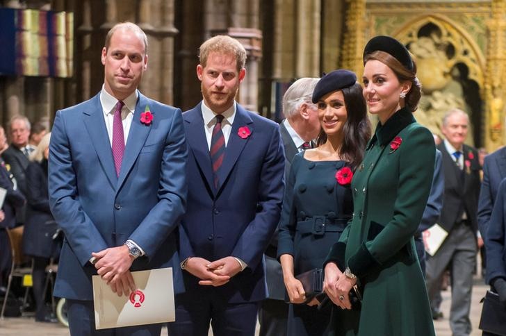 Prince William stands to the left, with Prince Harry to his right, followed by Meghan and Kate. The foursome sport poppies.