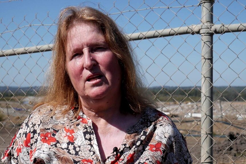 Conny Turni looks angry standing in front of a fence at the landfill site near Ipswich.