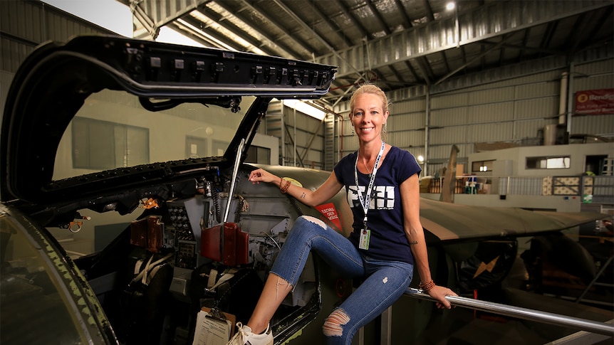 Melinda Andersson sits near the open cockpit of the F1-11 at HARS.