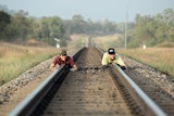 Two people lying on rail line.
