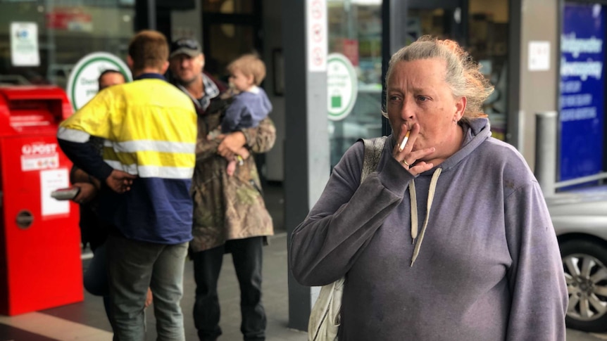 A woman smokes a cigarette outside a shopping centre