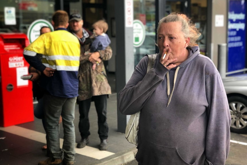 A woman smokes a cigarette outside a shopping centre