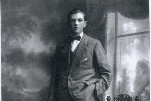 Black and white photo of young man in suit and bow tie for camera