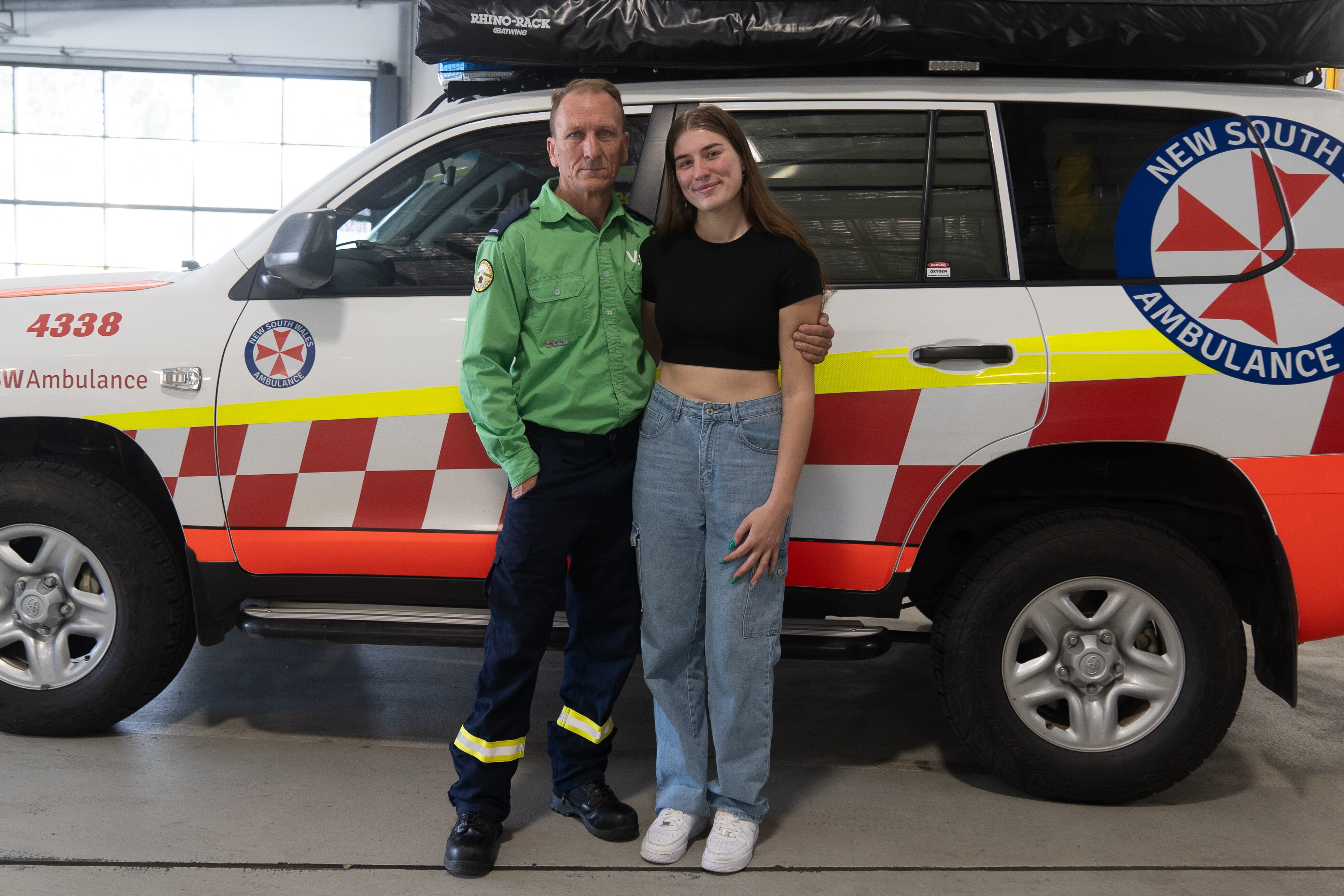 A man with an arm around a woman standing together in front of an ambulance