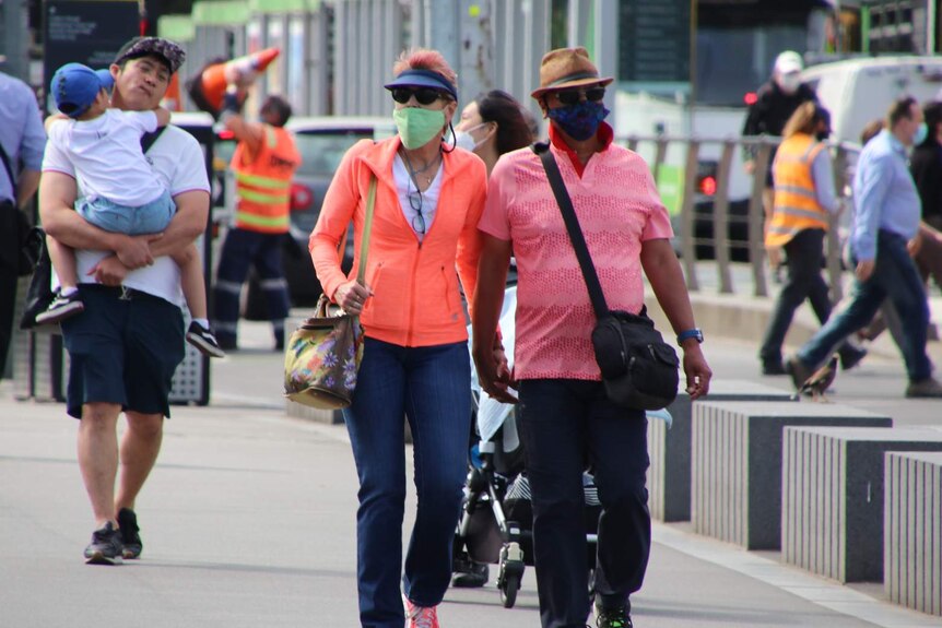 People wear face masks as the walk along a city street.