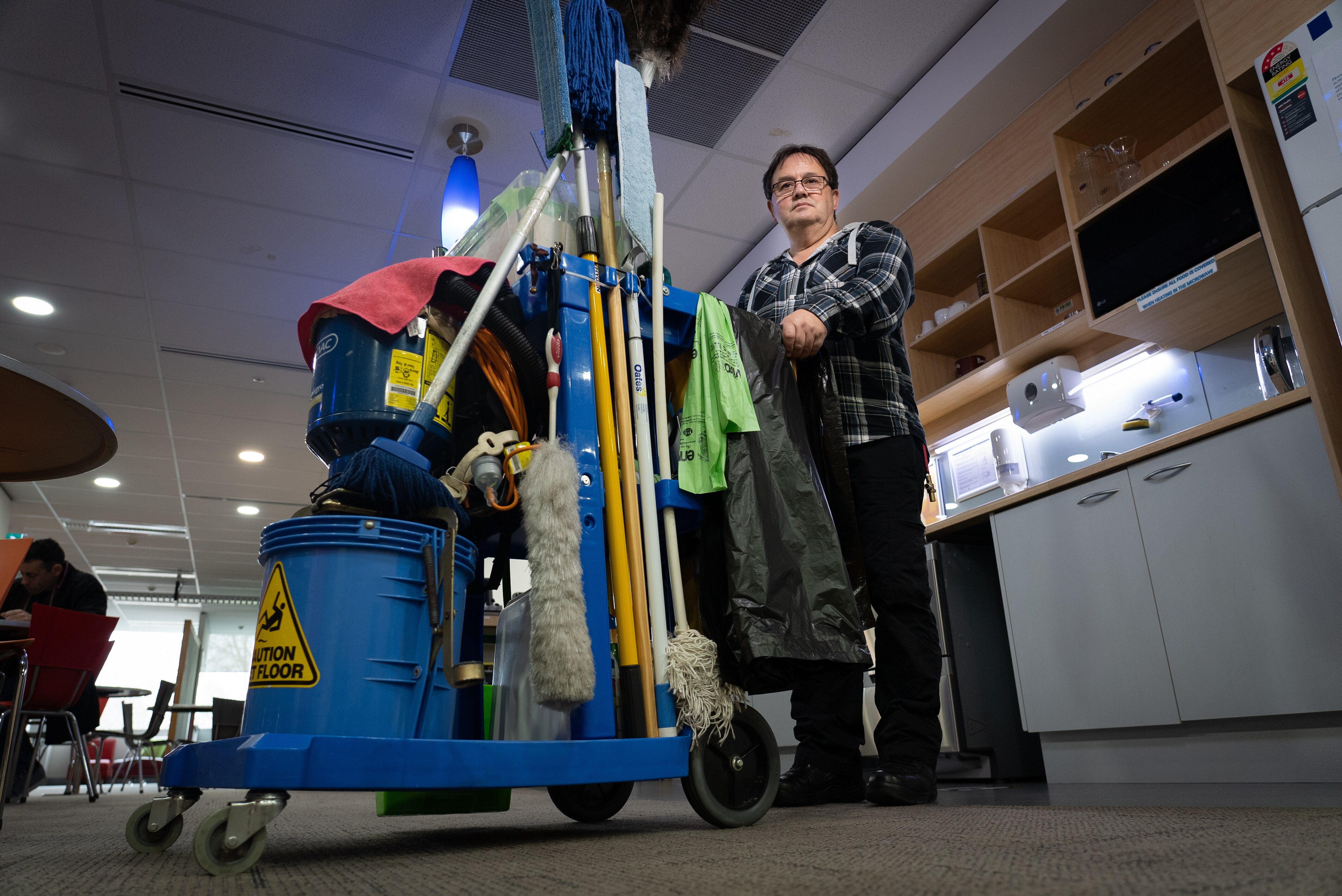 Man holding a trolley full of cleaning equipment.