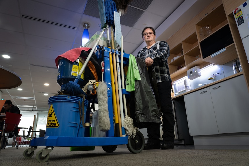 Man holding a trolley full of cleaning equipment.