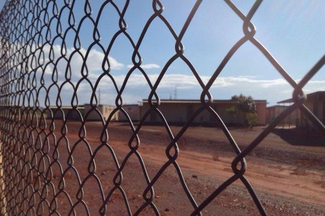 A donga sits behind a wire fence.