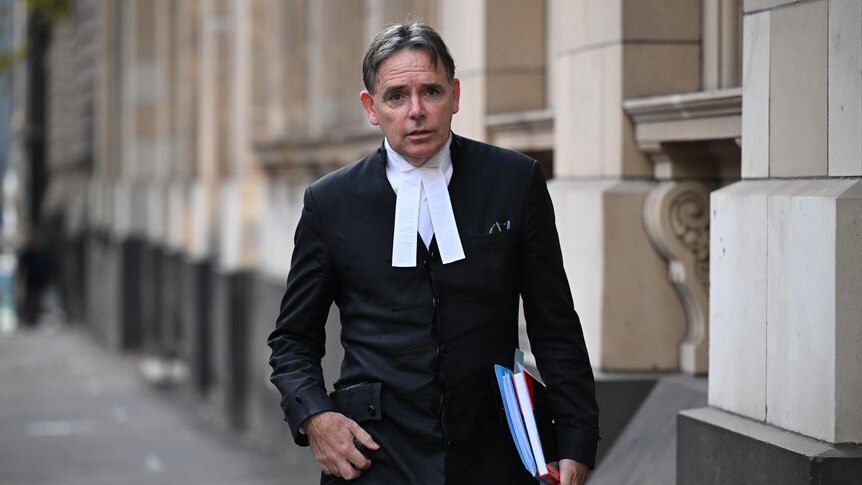 Dermot Dann holding books under one arm walking into court. 