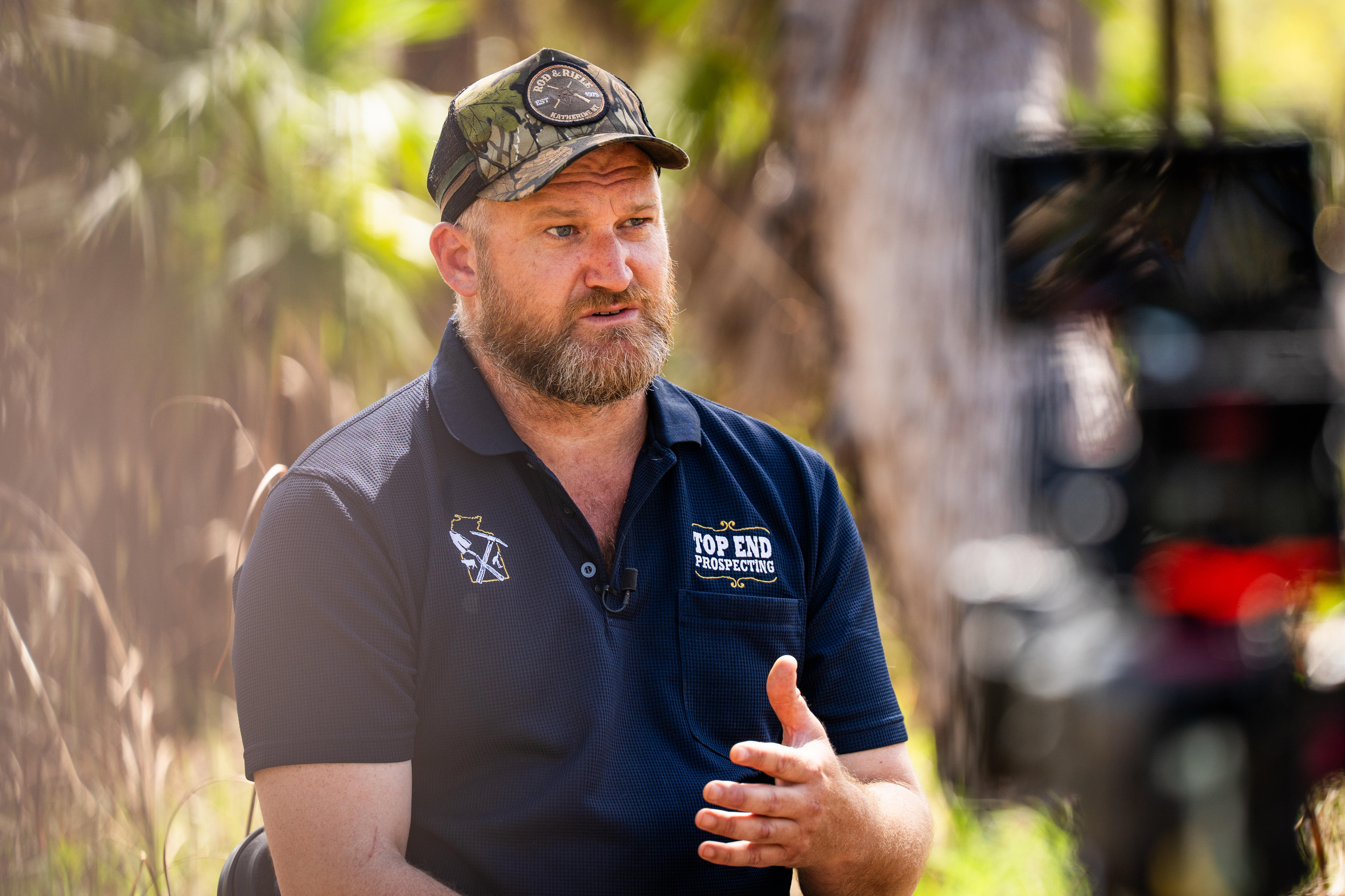Man in polo and trucker hat talks while being interviewed 