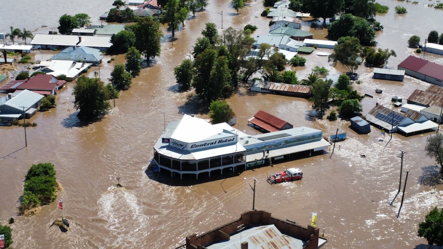 Aerial view of several homes and a large building under flood waters