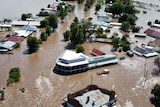 Aerial view of several homes and a large building under flood waters