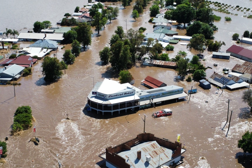 Vue aérienne de plusieurs maisons et d'un grand bâtiment sous les eaux de crue.