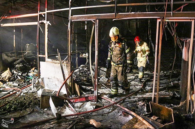Firefighters walking through a burned out building at night