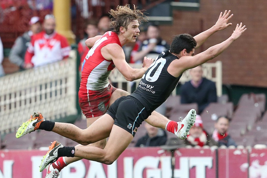 Sydney's Dane Rampe (L) kicks a goal despite an attempted block by Port Adelaide's Chad Wingard.