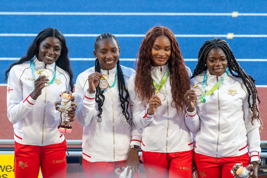Female athlete wearing white and red pose with medal