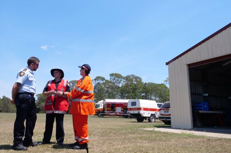 Emergency services personnel discuss firefighting plans outside the Yandaran Rural Fire Station shed.